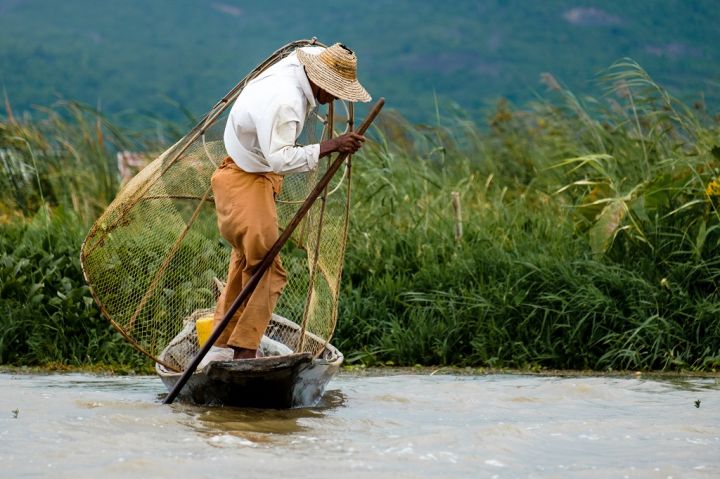 asian-fisherman-with-the-net-on-a-boat-inle-lake-PNYKZK8.jpg