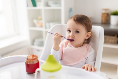 baby-girl-with-spoon-eating-puree-from-jar-at-PJTFBNU.jpg