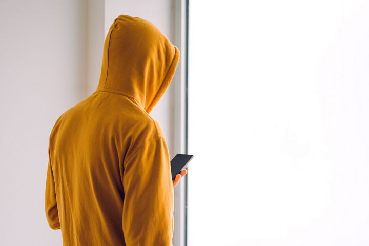 man-with-hoodie-and-mobile-phone-standing-by-the-PY9XD6K.jpg