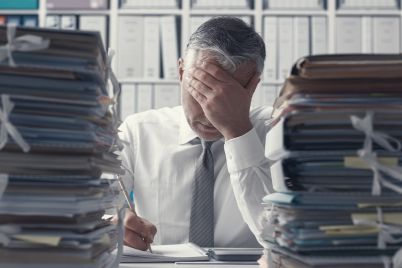 stressed-business-executive-and-piles-of-PX89VUH.jpg