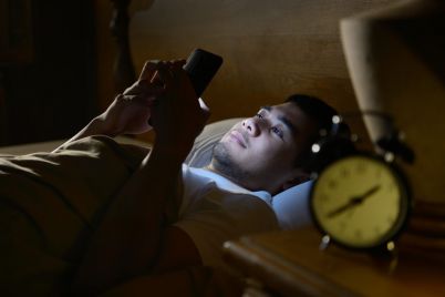 young-man-using-a-smartphone-in-his-bed-at-night-P88RXTS-e1550825035963.jpg